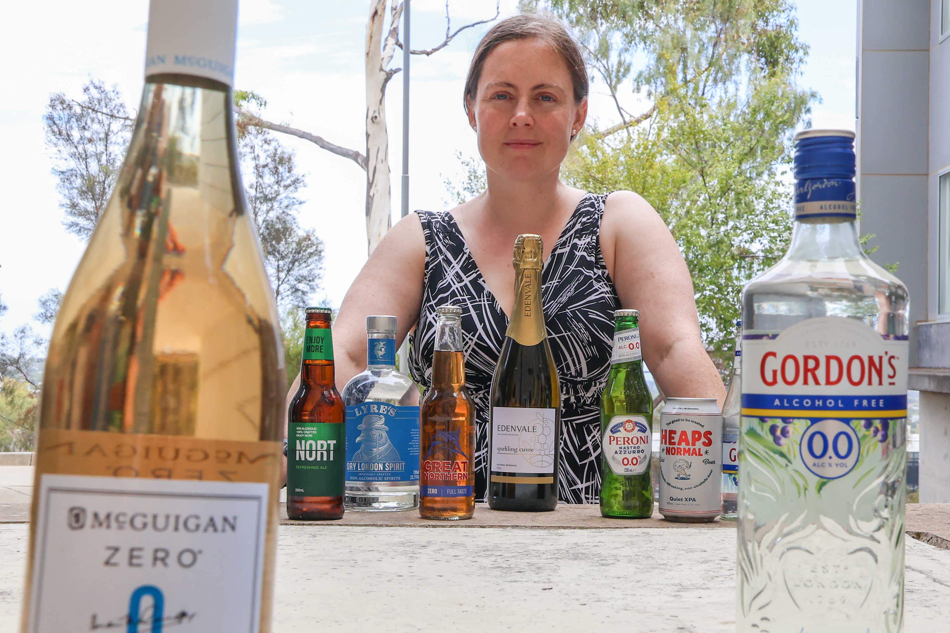a table with drinks bottle and a woman sitting next to table