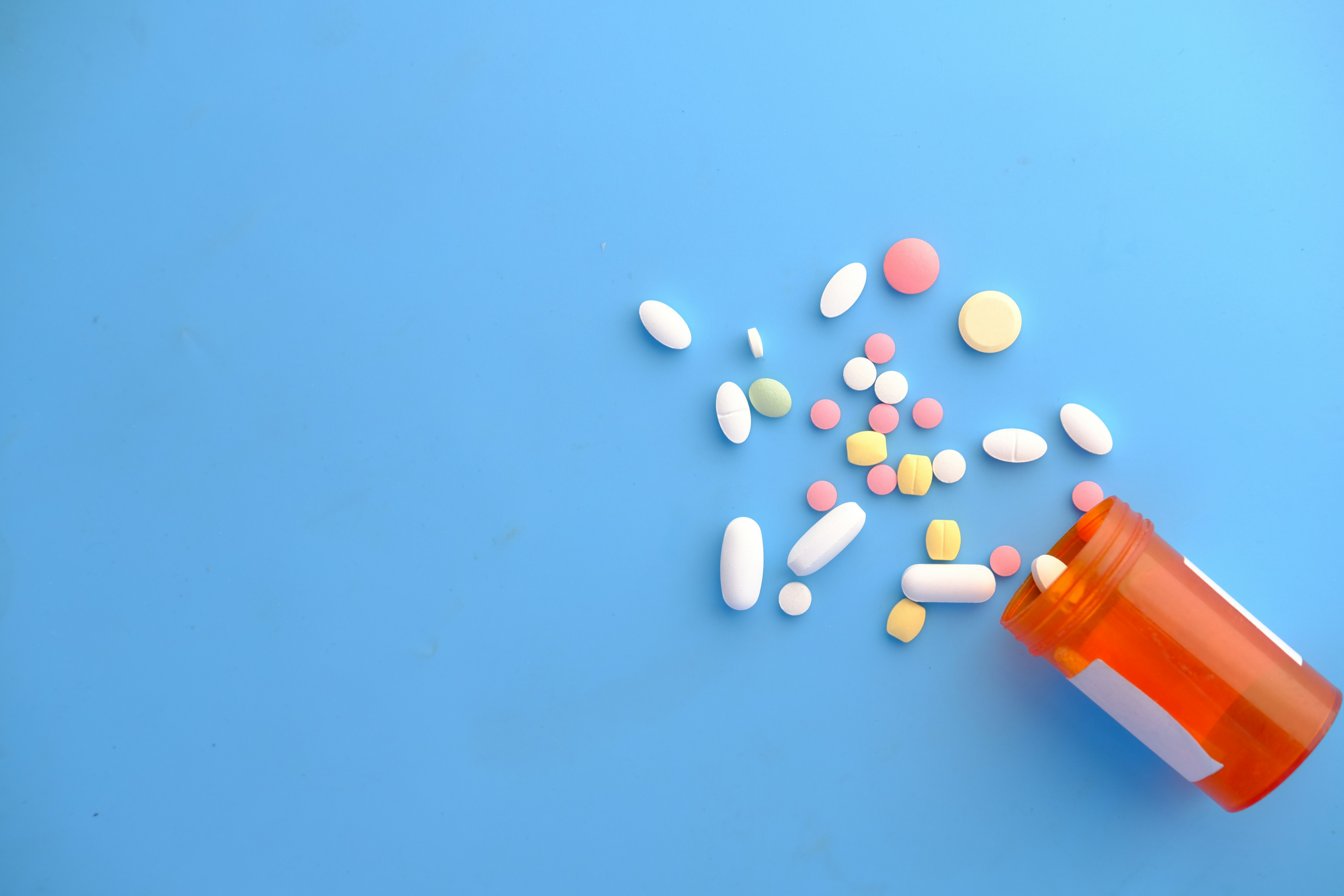 Open pill bottle on blue background stock