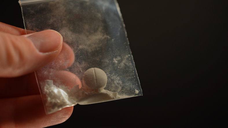 Hand holding small bag with a pill inside