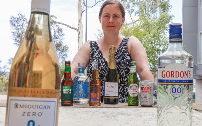 a table with drinks bottle and a woman sitting next to table