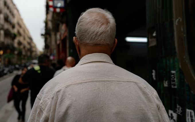 Elderly man standing in the street with his back to the camera