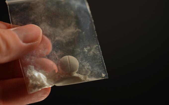 Hand holding small bag with a pill inside