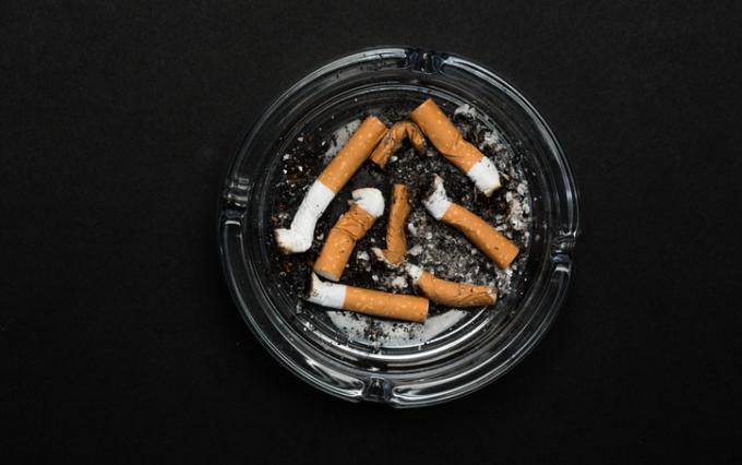Ashtray with cigarettes on black background